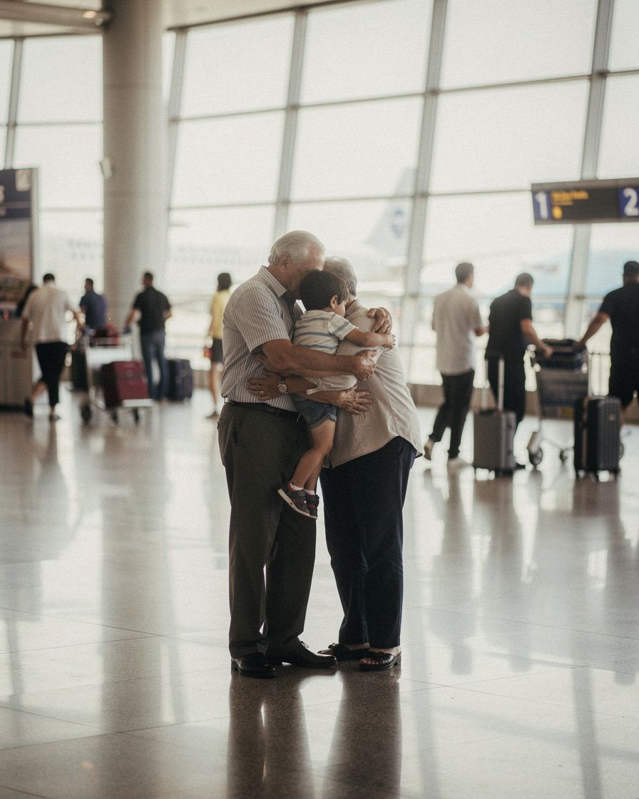 Grandparents embracing a small child in an airport arrivals hall